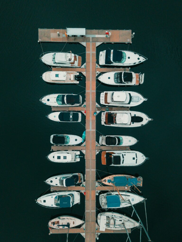 Top-down aerial view of multiple boats docked in slips at a marina.